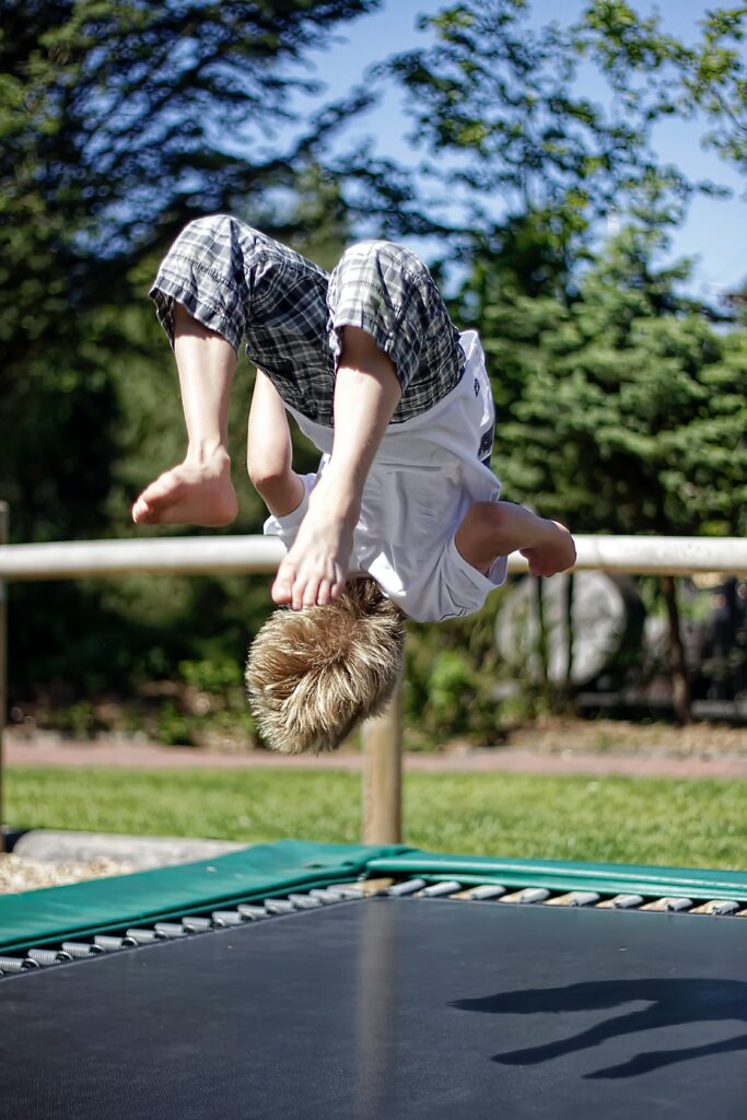 boy doing back-flip on outdoor trampolline