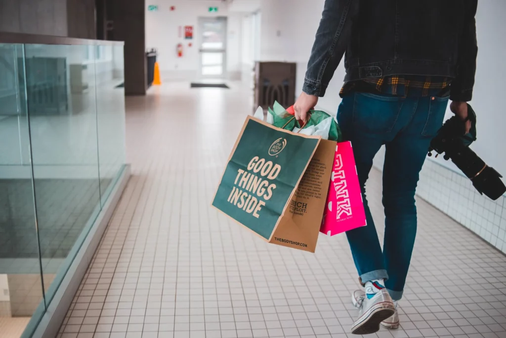 A consumer walks through a mall holding two shopping bags