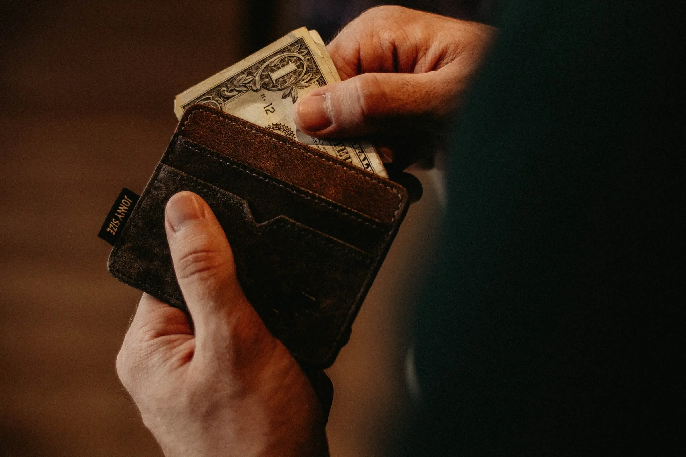 Individual removing a dollar bill from their wallet
