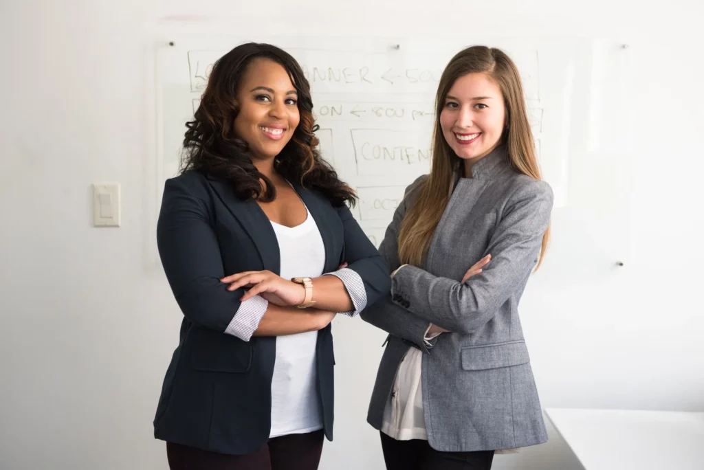 Two workplace professionals stand in front of a whiteboard business plan
